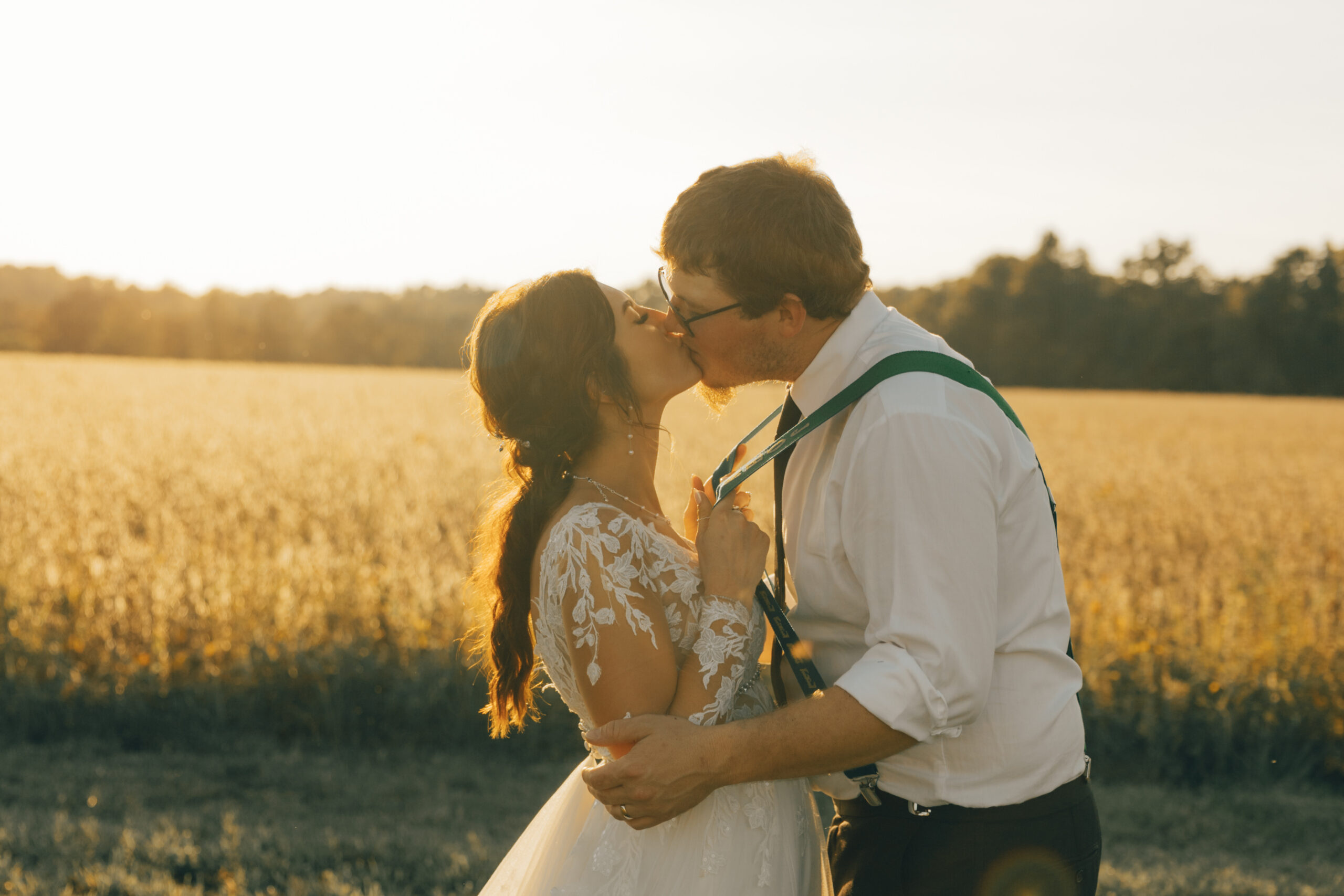 Bride kissing Groom holding his suspensers