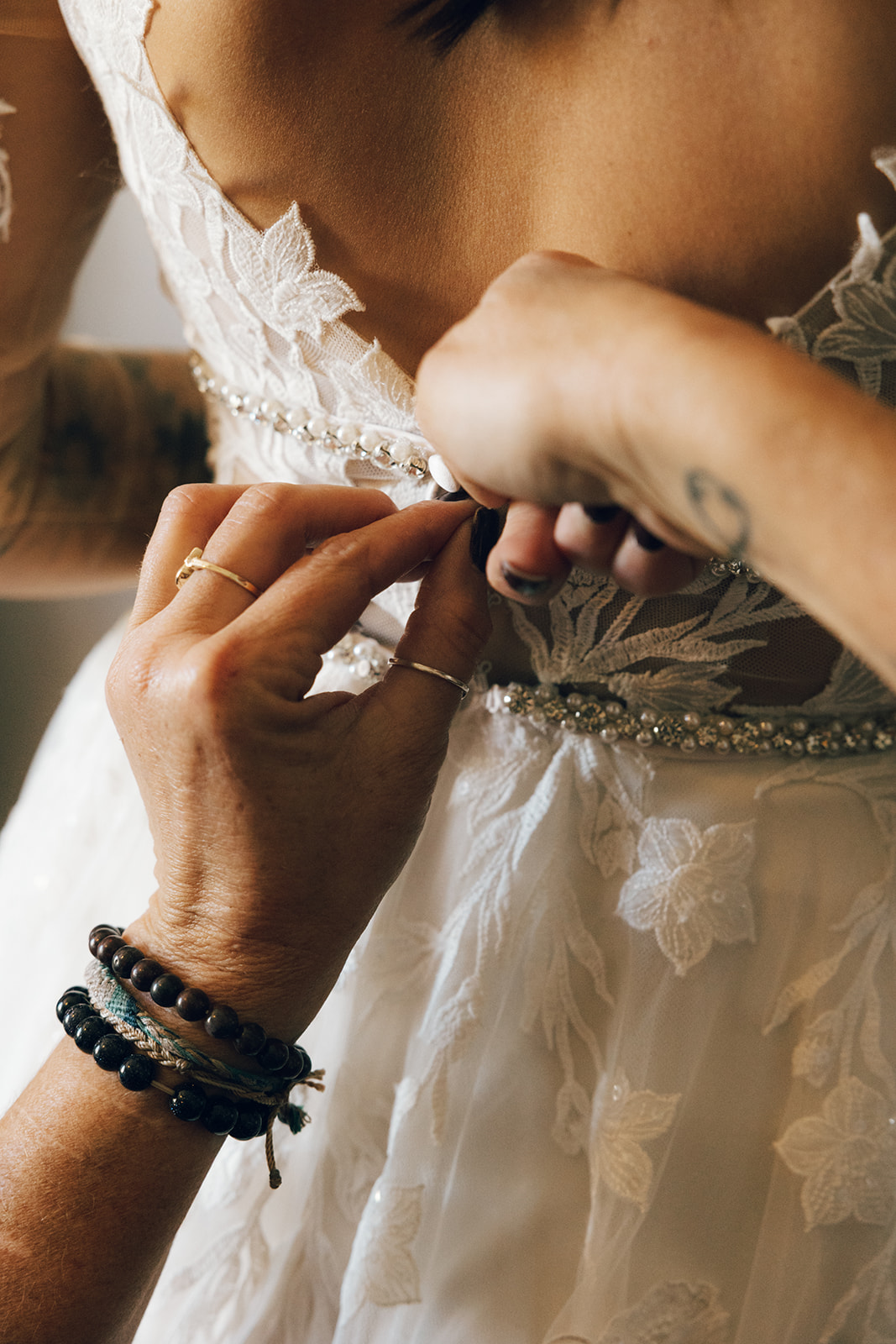 Mom helping bride put on wedding dress